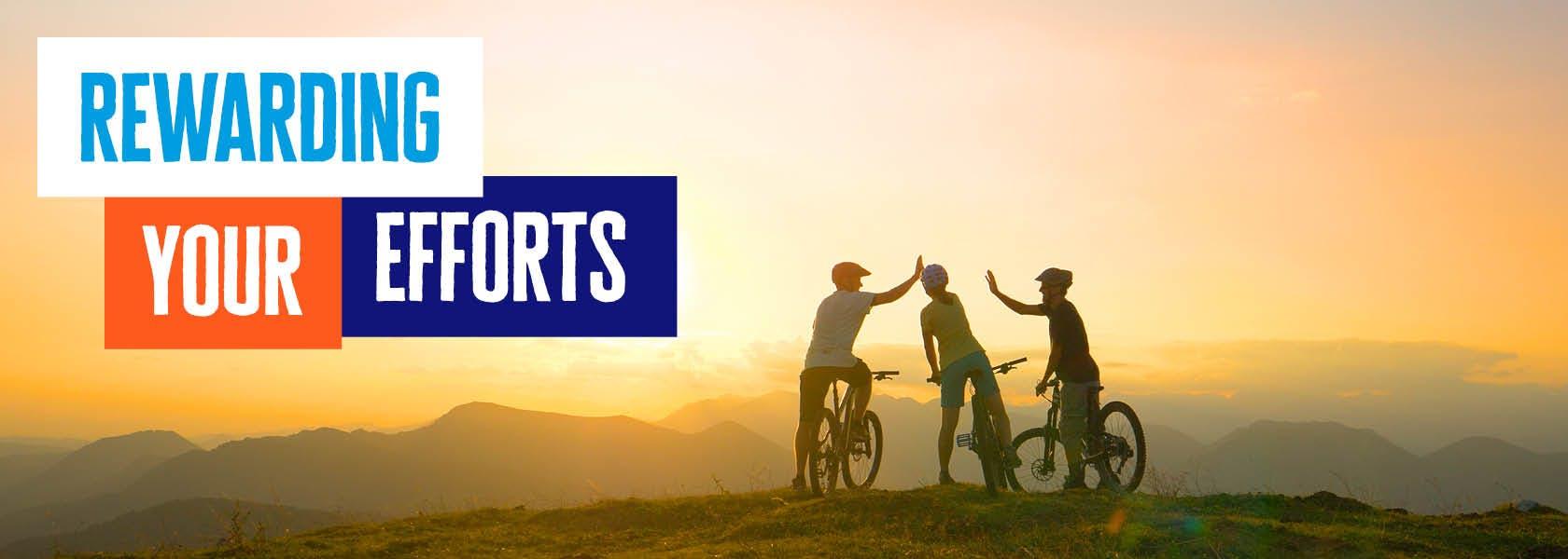 Three Diabetes UK cyclists high fiving on a hilltop at sunset as they take on their UK Wide Cycle Ride challenge